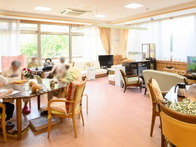 明るい共有スペース ラウンジ 大きな窓から自然光が差し込む明るいスペースです。落ち着いた雰囲気で、皆が談笑しています。