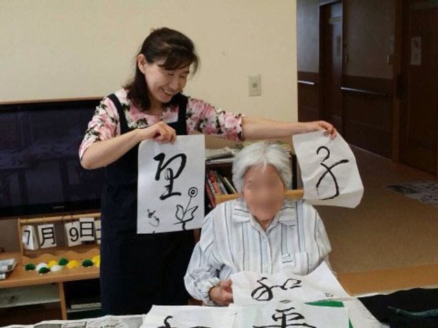 書道活動を楽しむ様子 書 笑顔で書道に取り組む方々がいる、和やかな雰囲気の室内です。創作活動を通じて、日々の生活に潤いを提供しています。