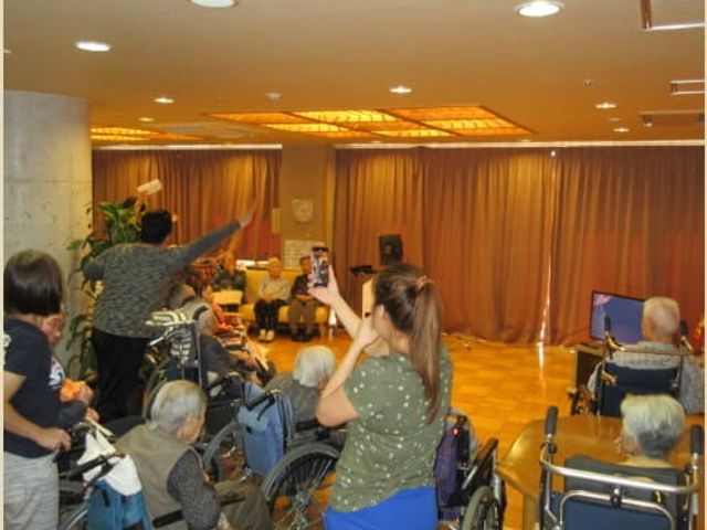 住民活動の光景 居室 広々とした明るい空間で、住民がリラックスして活動を楽しんでいます。笑顔があふれる場面です。