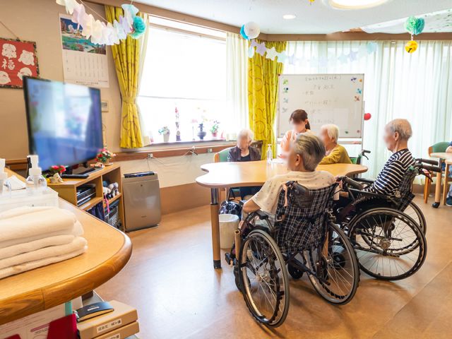 車椅子の利用者がいる共有スペース 共有スペース 明るい日差しの中で、利用者が談笑しながら過ごす暖かな空間です。車椅子を利用していても、ゆったりとくつろげる広々とした部屋があります。