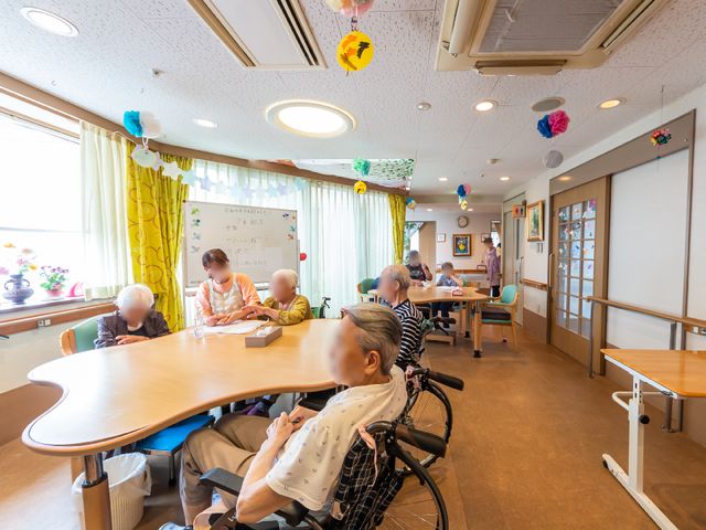 多世代共有スペース 共有スペース 広々としたラウンジで、利用者の方々がゆったりと過ごされています。明るく開放的な雰囲気が、作業や会話を楽しむ場を提供しています。