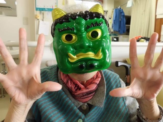 お面をつけた笑顔の方 共有スペース 元気なスタッフがいる活気ある空間です。手を広げた笑顔で、楽しいひとときを演出しています。