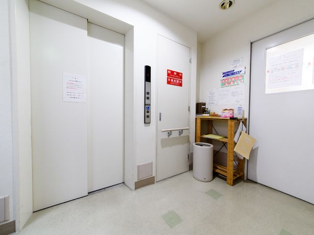 廊下のエレベーターと掲示物 エレベーター 清潔感のある廊下には、エレベーターへのアクセスが容易です。掲示物からは、日々の情報共有が大切にされている様子が伺えます。