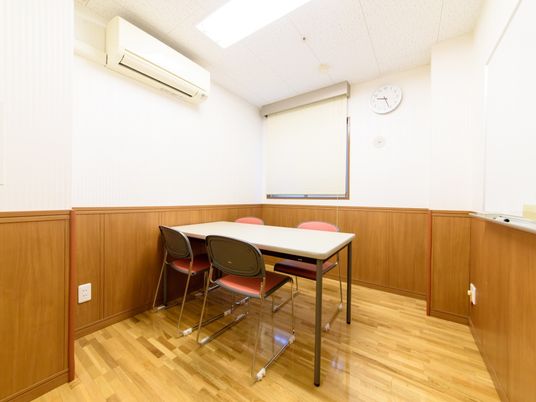 談話室にはエアコンが設置されている。テーブルの周りには椅子が並べられている。壁にはホワイトボードがある。