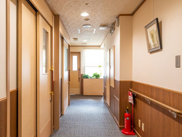 清潔な廊下の一部分 廊下 手すり付きの廊下は清潔感があり、ゆったりとした歩行スペースが確保されています。壁に飾られたアートが温もりのある雰囲気を演出しています。