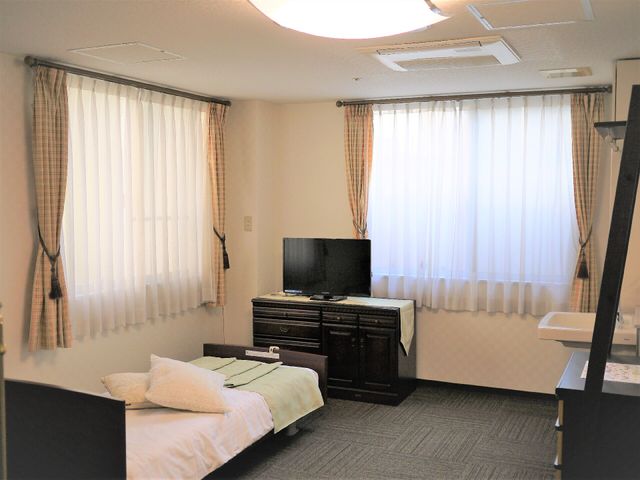 清潔な個室の居室 居室 落ち着いた色合いの居室には、快適な生活をサポートする家具が整い、窓からは自然光が差し込みます。