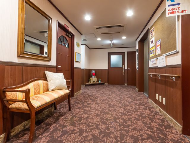 廊下の中央にベンチ ベンチが置かれた落ち着いた色調の廊下です。通路は広く、壁には案内板も備えてあり、気軽に休憩できる空間が確保されています。