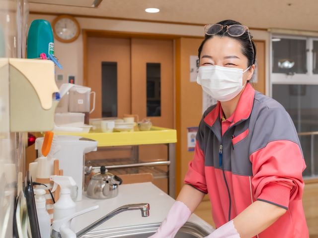 笑顔のスタッフとキッチン 清潔感あふれるキッチンで、明るく元気なスタッフが笑顔で作業をしています。品格と活気を感じさせる仕事環境です。