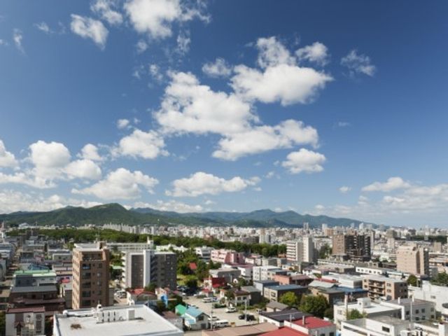 青空と街並みの眺望 景色 広々とした視界が開ける立地で、日々の生活に心地よい眺望を提供します。緑豊かな景色の中で、新たな職場をお考えの方に最適です。