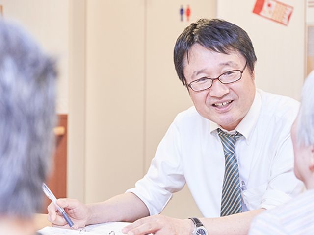 スタッフと入居者の対話シーン スタッフイメージ スタッフが利用者と笑顔で会話を楽しむ様子です。コミュニケーションが活発な職場です。