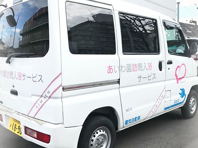 訪問送迎車 看板 訪問サービスの車両が施設の外に停まっています。この車で利用者様の送迎を行います。