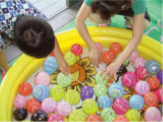 水遊びを楽しむ人々 イベント 彩り豊かなボールが散りばめられたビニールプールで、利用者の方々が水遊びを楽しんでいます。コミュニケーションを重視した活動が魅力です。
