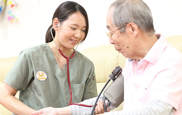 血圧測定するスタッフと利用者