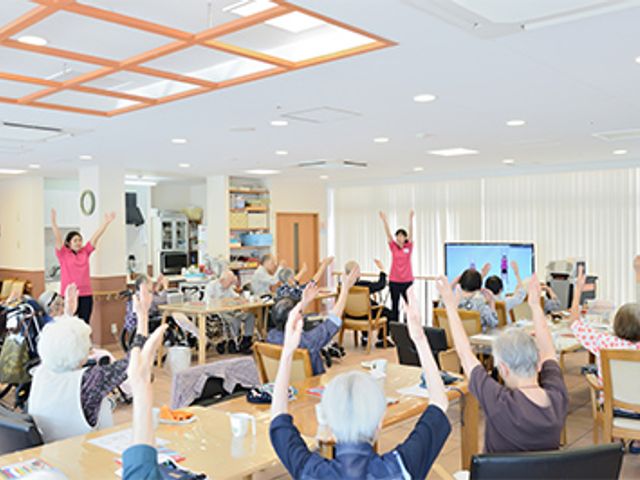 体操する人々の共有スペース 多目的室   明るい多目的室で、体を動かす体操レッスンが行われています。健康維持に役立ちます。