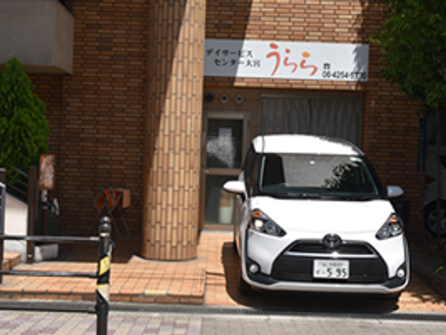 送迎車のある外観 外観   レンガ調の外観前に送迎車が停まっており、出入りしやすい印象です。施設名の看板も見え、来訪時の目印になりそうです。