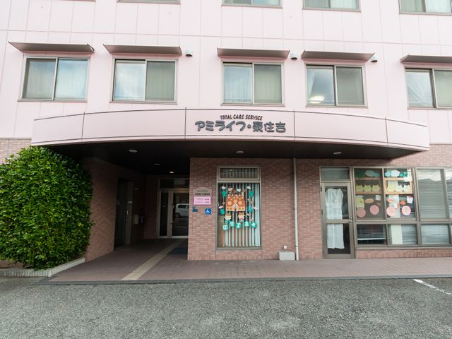 ピンクの建物のエントランス 外観 明るく開放的なエントランスは訪れる人々を暖かく迎えます。身近に感じる環境で、新たな職場を考える一歩を踏み出しませんか。
