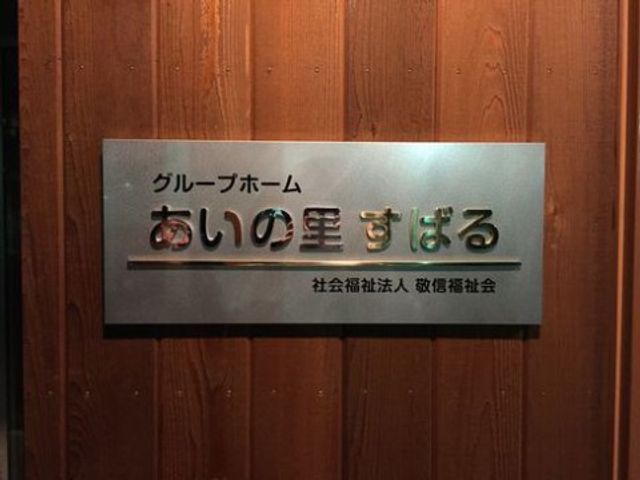 看板のクローズアップ 看板 温かみのある木目調の壁に設置された、こちらの施設のシンボルとも言える看板です。訪れる方々への心地よい歓迎の象徴となっています。