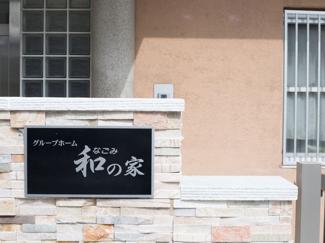施設の看板 外観 石造りの壁に設置された施設名が記された看板です。落ち着いた色合いで周囲の雰囲気にも合っています。