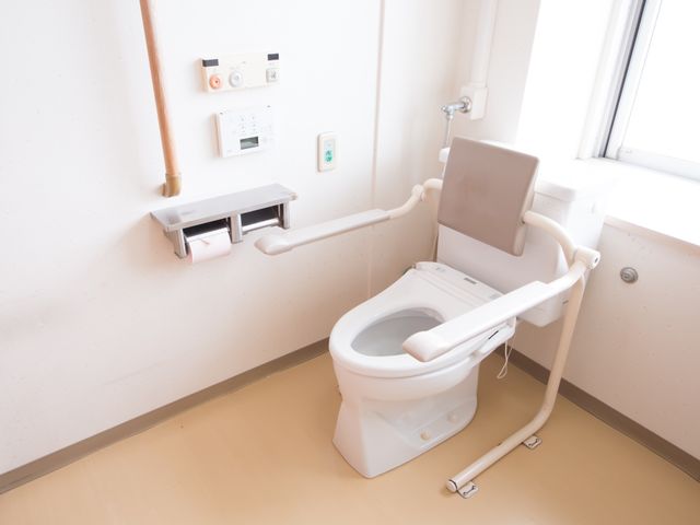 手すり付きトイレ設備 トイレ 安全に配慮された手すりや補助座席を備えた清潔なトイレです。日々の生活の中で安心してご使用いただけます。