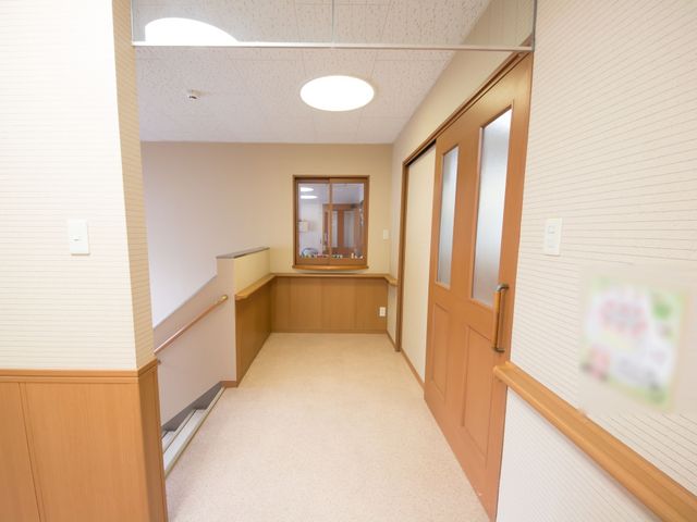 清潔な廊下とスタッフルーム 廊下 明るく清潔な廊下が確保され、向かいにはスタッフが対応するカウンターが見えます。ここで働くときは、快適な環境を享受できそうです。