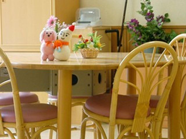 飾り付き木製テーブルの食堂 食堂   木製の丸テーブルと椅子が並ぶ、落ち着いた雰囲気の食堂です。小物が飾られ、やわらかな空間づくりが感じられます。