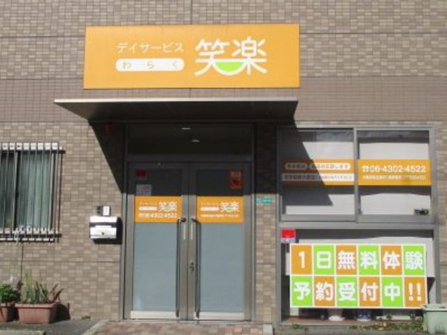 暖色系エントランス 鮮やかな看板が目印の入口は、訪れる皆様を温かく迎えます。清潔感があり、働く環境として魅力的です。