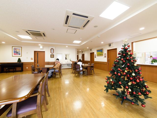 広々とした明るい食堂 共有スペース 広々とした食堂で、利用者がゆったりと座ってくつろいでいます。季節の装飾が施された空間は、日々の生活に彩りを加えています。