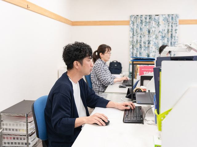 コンピュータ作業をする人々オフィス スタッフイメージ 職員がパソコンで業務を進めています。静かで集中できる環境が整っています。
