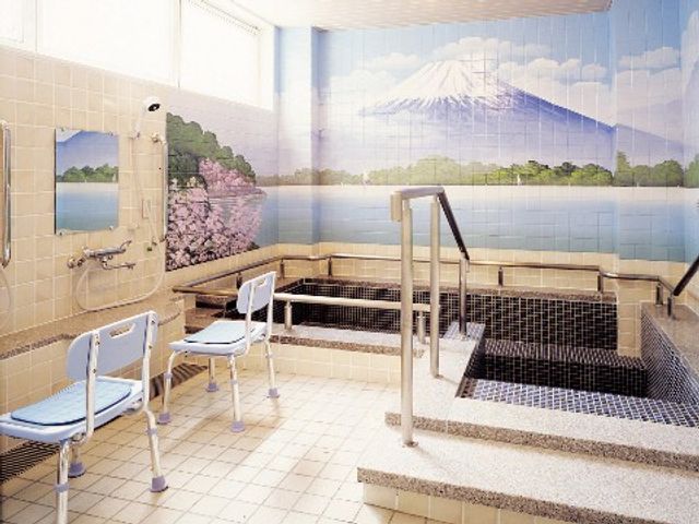 浴室と富士山のタイルアート 浴室 壁に描かれた富士山のタイルアートが印象的な浴室は、利用者のリラックスをサポートします。手すりや椅子も備え、安全に配慮された設計です。
