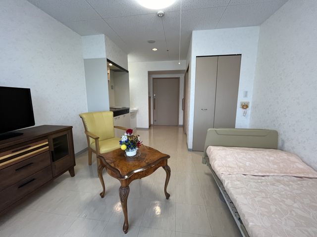 ゆったり過ごせる居室 居室 ベッドとテレビが備えられた空間は、清潔感があり、くつろぎやすい造りになっています。お花が飾られたテーブルが、居心地の良い雰囲気を演出しています。