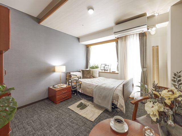 居室のインテリアと家具 居室 ゆったりとしたベッドと暖かい照明の空間。快適な生活を支える配慮が見受けられます。