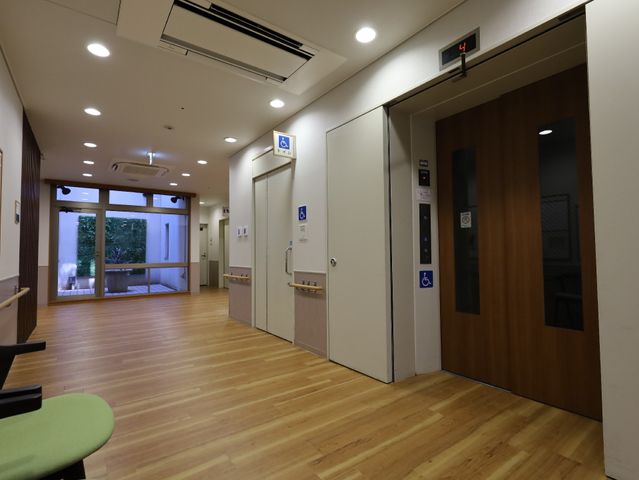 清潔感のある廊下の一角 エレベーター 落ち着いた色合いの壁と床が、快適な移動空間を提供しています。明るく開放的な通路が特徴です。