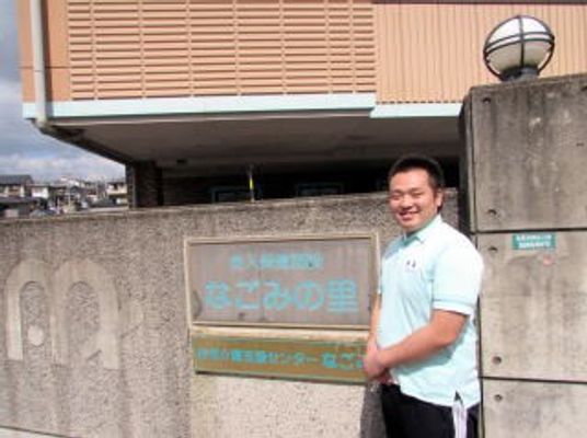 施設看板と男性スタッフの外観  