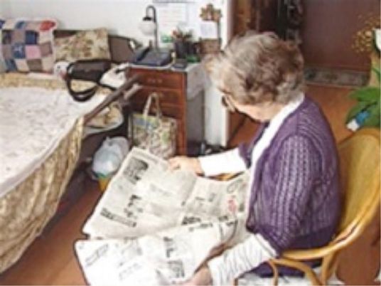 新聞を読む高齢者居室