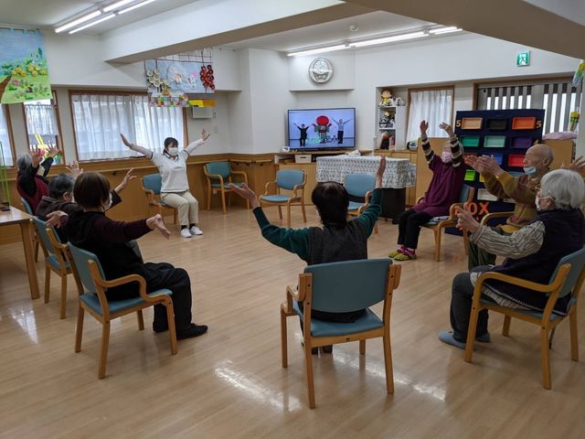 機能訓練中の居室 スタッフの指導のもと、利用者が体操をしている様子です。健康維持に役立つプログラムが充実しております。