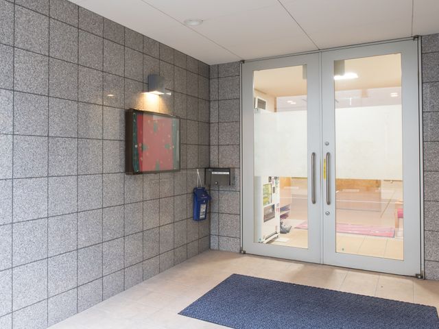 エントランスの自動ドア 玄関 広々としたエントランスは、来客を優しく迎え入れます。清潔感のある設計で、明るく穏やかな雰囲気が漂っています。