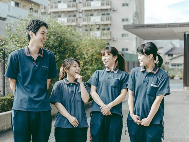 笑顔のスタッフたちの様子 スタッフイメージ リラックスした雰囲気で働ける環境が整っています。笑顔の職員たちが和やかに会話を楽しんでいます。