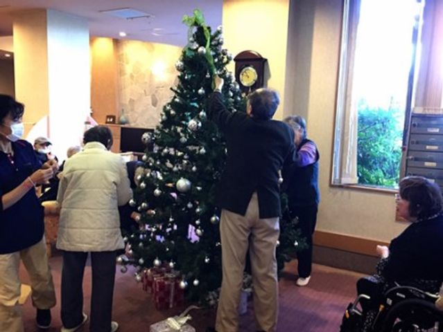 クリスマスツリー飾り付け 共有スペース 利用者と職員が一緒になり、クリスマスツリーの装飾を行っています。祝祭の装いも楽しむことができ、季節行事に対する心遣いが感じられます。