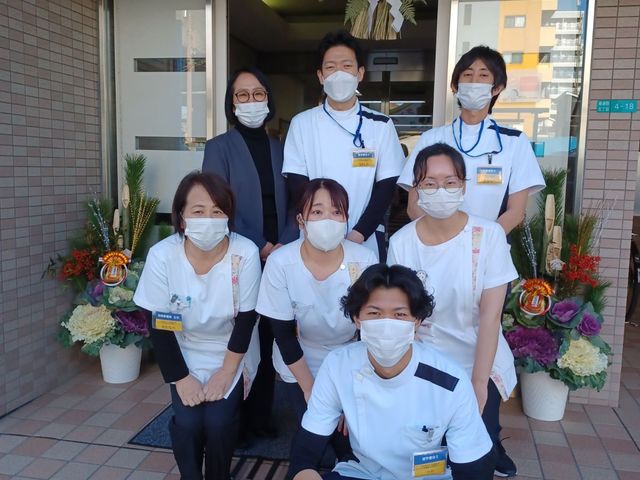 スタッフ集合のエントランス エントランス   明るい入口前でスタッフが並んでおり、和やかな雰囲気が伝わります。来訪者を迎える場の様子が見え、働くイメージを持ちやすいです。