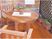 木製の明るい色のデッキに、同系色の木製の丸テーブルと座面が大きな椅子が置かれている。テーブルの中央に花鉢が1つ置かれている。