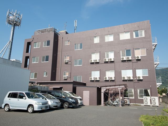 茶色の建物の外観 外観 広々とした駐車スペースを備え、快適な通勤が見込める建物です。窓とエアコンが完備された外壁は、機能性に富んでいます。