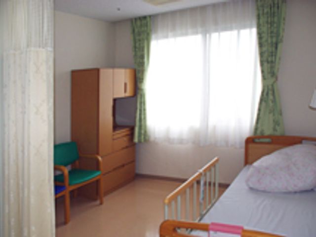 窓辺のベッドと椅子の居室 居室 自然光がたっぷり入る居室で、落ち着いた雰囲気です。ベッドの隣にはくつろげる椅子があります。