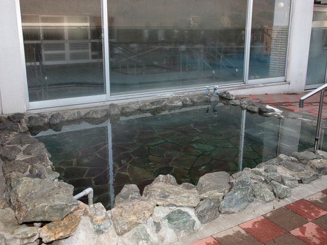 岩に囲まれた浴槽の庭 中庭   石組みで囲まれた落ち着いた空間です。窓越しに建物内が見え、ゆったりとした雰囲気が伝わります。