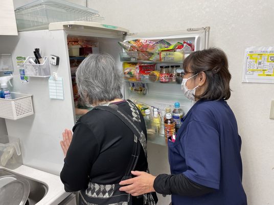 利用者とスタッフが冷蔵庫を見るキッチン  