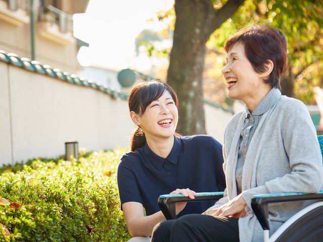 スタッフと利用者の笑顔 スタッフと利用者の笑顔 自然豊かな庭で、スタッフと笑い合うひとときが心地よい環境です。リラックスできる時間を提供します。