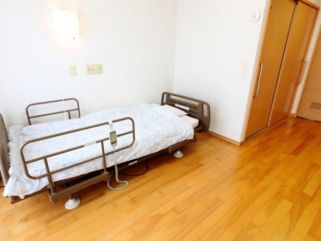居室のベッドと床 居室 ベッド周りにはゆとりの空間があり、明るい光が差し込む快適な居室です。安全のための手すりも完備しています。