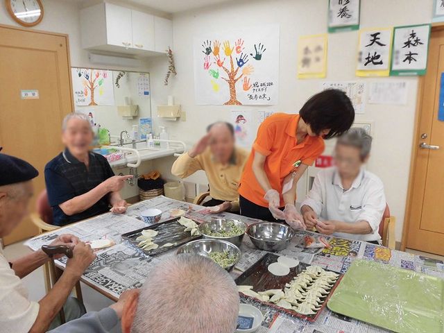 料理を楽しむ様子 多目的室 みんなで餃子作りを楽しめる和気あいあいとした雰囲気です。スタッフが丁寧にサポートしています。