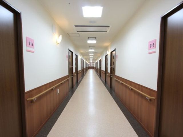 清潔で明るい廊下 プライバシー 手すりがついた長い廊下は、ゆとりを持って歩ける設計になっており、清潔感が感じられます。