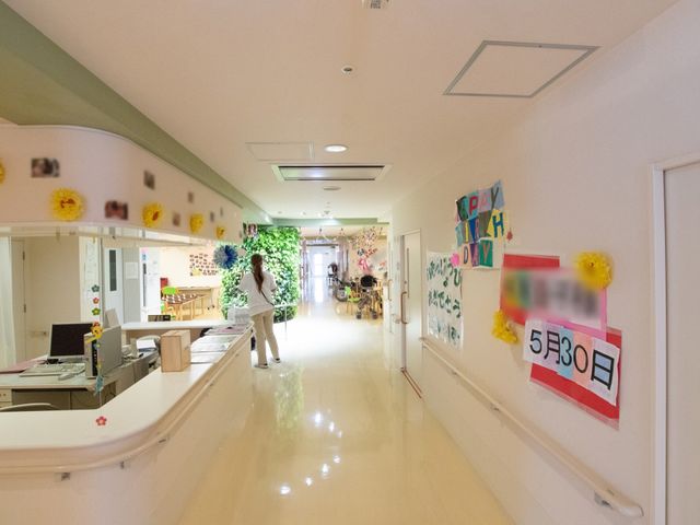 廊下とスタッフ様子 廊下 温もりある装飾が施された廊下で、職員の方が一生懸命働いています。手作りの飾りや案内板があり、訪れた方々を優しく迎え入れています。