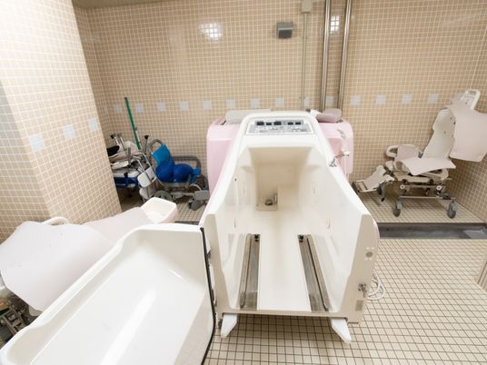 介護用の特殊浴槽はきれいに磨かれており、十分な奥行きがある。浴室内は広々とした作りであり、入浴用の車椅子などが余裕をもって収納されている。